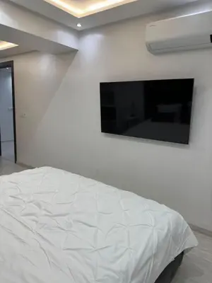 a white bedroom with a bed with a tv on the wall at Duplex 3 chambres centre ville in Marrakech