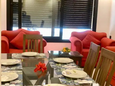 a dining room with red chairs and a glass table at Appartement Mazal in Marrakech