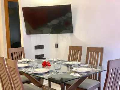 a dining room table with chairs and a television on the wall at Appartement Mazal in Marrakech