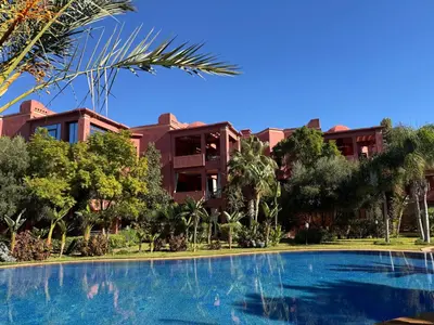 a resort with a swimming pool in front of a building at Beldi garden - appartement avec jardin et gouvernante in Marrakech