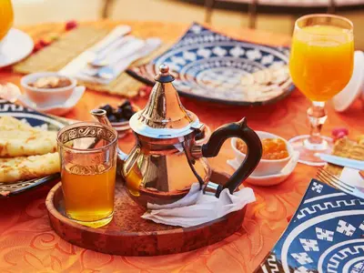 a table with a tea kettle and a glass of orange juice at Beldi garden - appartement avec jardin et gouvernante in Marrakech