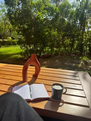 a book and a cup of coffee on a wooden table at Beldi garden - appartement avec jardin et gouvernante in Marrakech