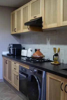 a kitchen with a stove and a washing machine at Beldi garden - appartement avec jardin et gouvernante in Marrakech