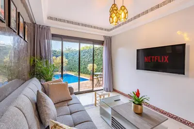 a living room with a couch and a tv at Magnifique Duplex avec piscine privée in Marrakech