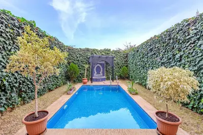 a swimming pool in a yard with two potted trees at Magnifique Duplex avec piscine privée in Marrakech