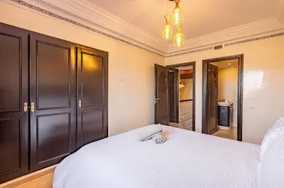 a bedroom with a white bed and black cabinets at Magnifique Duplex avec piscine privée in Marrakech