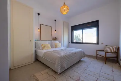a bedroom with a bed and a window and a chair at Villa Yliane in Marrakech