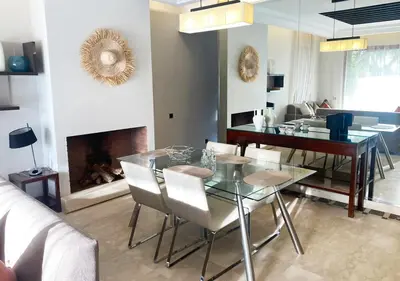 a dining room with a glass table and a fireplace at Luxueuse Appart Vizir 106 in Marrakech