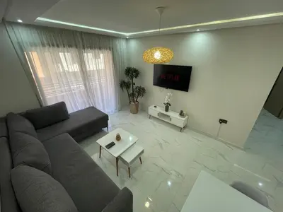 a living room with a couch and a tv on a wall at Modern Stay 3 bedroom City Center with Balcony in Marrakech