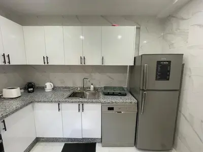 a kitchen with white cabinets and a stainless steel refrigerator at Modern Stay 3 bedroom City Center with Balcony in Marrakech