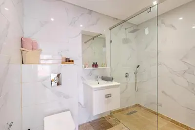 a white bathroom with a shower and a sink at Large elegant 2BR Apt in Gueliz in Marrakech
