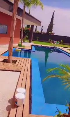 a swimming pool with blue water and a wooden deck at Villa akiba in Marrakech
