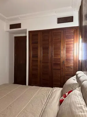 a bedroom with a bed and wooden closet at Marrakech Oasis, Residence Ennaim 1 in Marrakech