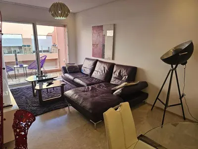 a living room with a leather couch and a table at Apparemment haut de gamme à l'hivernage in Marrakech