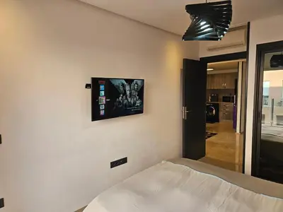 a bedroom with a bed and a tv on the wall at Apparemment haut de gamme à l'hivernage in Marrakech