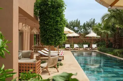a swimming pool with chairs and umbrellas next to a resort at Villa Ty Habibi - Super 5 Bedroom with Private Heated Pool by the Golf Amelkis in Marrakech