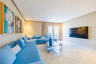 a living room with a blue couch and a tv at Luxueux appartement à Riad Garden in Marrakech