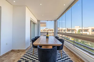 a dining room with a table and chairs and large windows at Luxueux appartement à Riad Garden in Marrakech