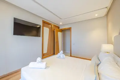 a bedroom with a white bed and a tv at Luxueux appartement à Riad Garden in Marrakech