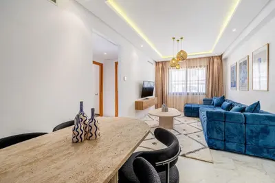 a living room with a table and a blue couch at Cozy & Elegant appart in hypercenter of Marrakech in Marrakech