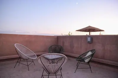 a patio with chairs and a table and an umbrella at Chic & Modern in City Center - Pool, IPTV & Comfort in Marrakech
