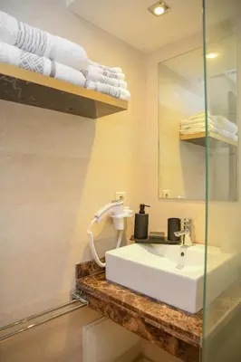 a bathroom with a sink and a mirror and towels at Chic & Modern in City Center - Pool, IPTV & Comfort in Marrakech