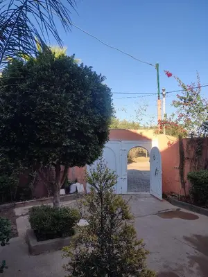 a white garage with a gate and a tree at Relaxing Family Home outside Marrakech in Marrakech