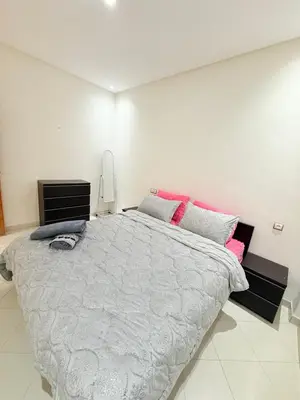 a white bedroom with a large bed with pink pillows at Appartement Tachfine lumineux FAMILY in Marrakech