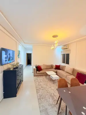 a living room with a couch and a tv at Appartement Tachfine lumineux FAMILY in Marrakech