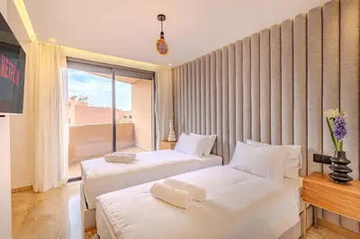 two beds in a room with a large window at Elegant 2BR apartment in Gueliz in Marrakech