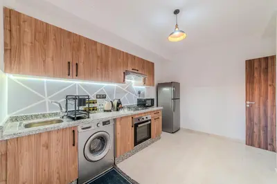 a kitchen with wooden cabinets and a washer and dryer at New! Apartment Gueliz 2 min M Avenue with Pool and 24h Security & Parking in Marrakech