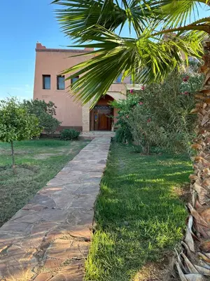 a stone walkway leading to a house with a palm tree at Magnifique Riad, Élégance et Charme Authentique à Marrakech in Marrakech