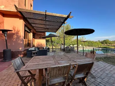 a wooden table with chairs and umbrellas on a patio at Magnifique Riad, Élégance et Charme Authentique à Marrakech in Marrakech
