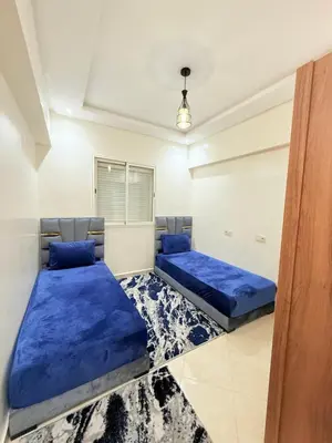 two beds in a room with blue sheets at Appart N35 COSY CONFORT FAMILY in Marrakech