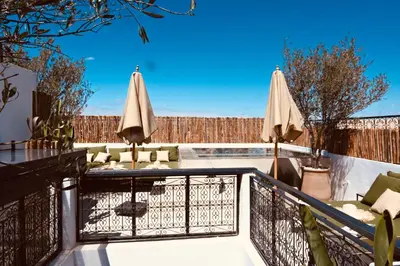a balcony with umbrellas and a swimming pool at Riad de charme Aïtana au cœur de la Médina in Marrakech