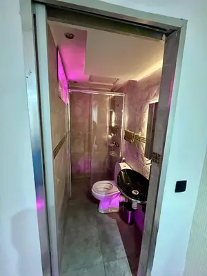 a bathroom with a toilet and a sink with pink lights at appartement guliz in Marrakech
