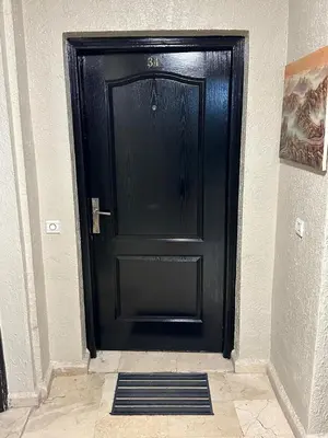 a black door in a hallway with a tile floor at Le Central Hivernage 8-37-44 face gare CTM et a 10mn de l'aéroport in Marrakech