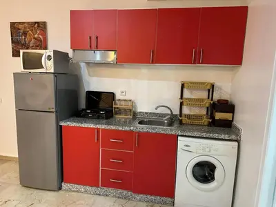 a kitchen with red cabinets and a washing machine at Le Central Hivernage 8-37-44 face gare CTM et a 10mn de l'aéroport in Marrakech