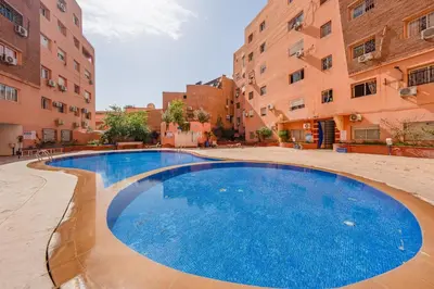 a large swimming pool in a courtyard between two buildings at Élégant Appartement 2 Chambres avec Piscine et Climatisation à Guéliz in Marrakech