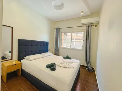 a bedroom with a bed with a blue headboard and a mirror at Élégant Appartement 2 Chambres avec Piscine et Climatisation à Guéliz in Marrakech