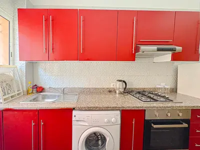 a kitchen with red cabinets and a washing machine at Élégant Appartement 2 Chambres avec Piscine et Climatisation à Guéliz in Marrakech