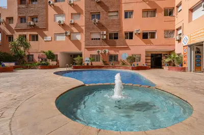 a fountain in a courtyard in front of a building at Élégant Appartement 2 Chambres avec Piscine et Climatisation à Guéliz in Marrakech