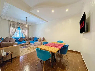 a living room with a table and blue chairs at Élégant Appartement 2 Chambres avec Piscine et Climatisation à Guéliz in Marrakech