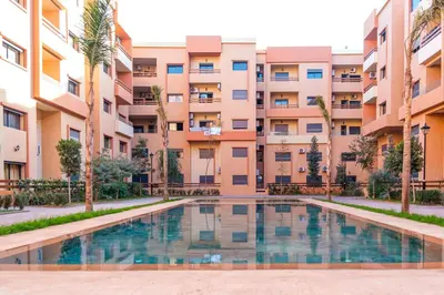 an apartment complex with a swimming pool in front of a building at 1BR Appart 2 min de M Avenue , Pool , Balcony & Parking & 24h j7 security in Marrakech
