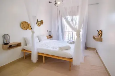 a bedroom with a bed with white curtains and a window at La Menara - 2 Chambres - Centre - Wifi in Marrakech