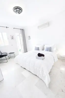 a large white bedroom with a large white bed at Luxe Studio 2min Carre Eden in Marrakech