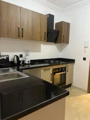 a kitchen with black counter tops and wooden cabinets at Cozy Apartment With Pool 5 min from Guéliz in Marrakech