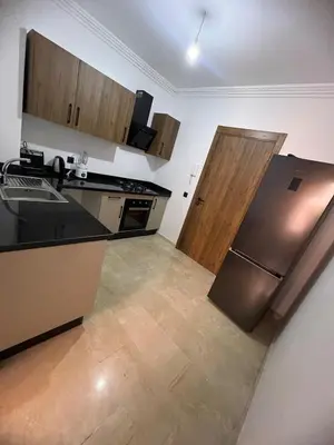 a kitchen with a stainless steel refrigerator and wooden cabinets at Cozy Apartment With Pool 5 min from Guéliz in Marrakech