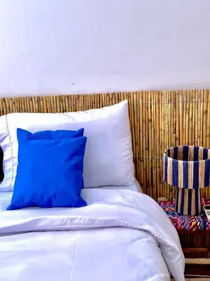 a bed with a blue pillow and a wooden headboard at Les Paniers de MARRAKECH 1 in Marrakech
