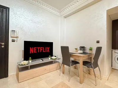 a dining room with a table and a television at Studio moderne avec terrasse, piscine et parking à Guéliz, Marrakech in Marrakech